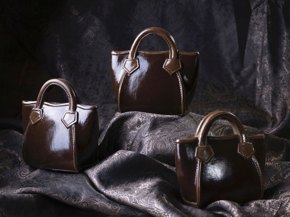 Handtasche Rigit aus Zartbitterschokolade mit zwei Henkeln und dekorativen Riemen