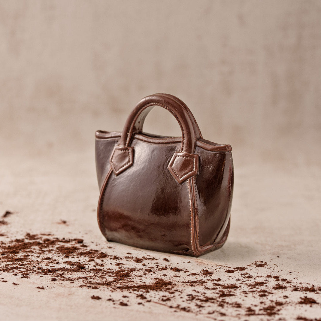 Handtasche Rigit aus Zartbitterschokolade mit zwei Henkeln und dekorativen Riemen